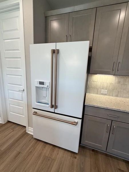 Modern kitchen with custom cabinetry, light stone countertops, and wood-look flooring. Modern kitchen with custom cabinetry, light stone countertops, and wood-look flooring.