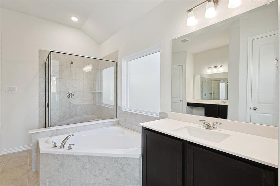 Bathroom with vanity, lofted ceiling, tile patterned floors, and shower with separate bathtub