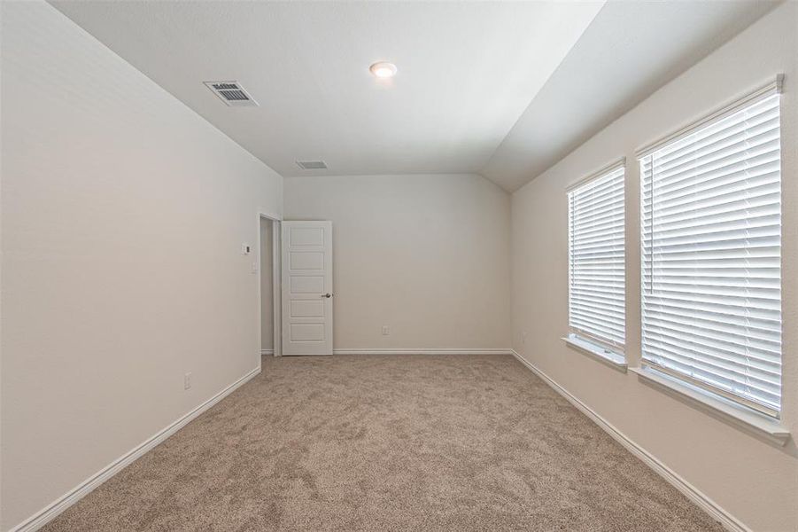 Empty room with light carpet and vaulted ceiling