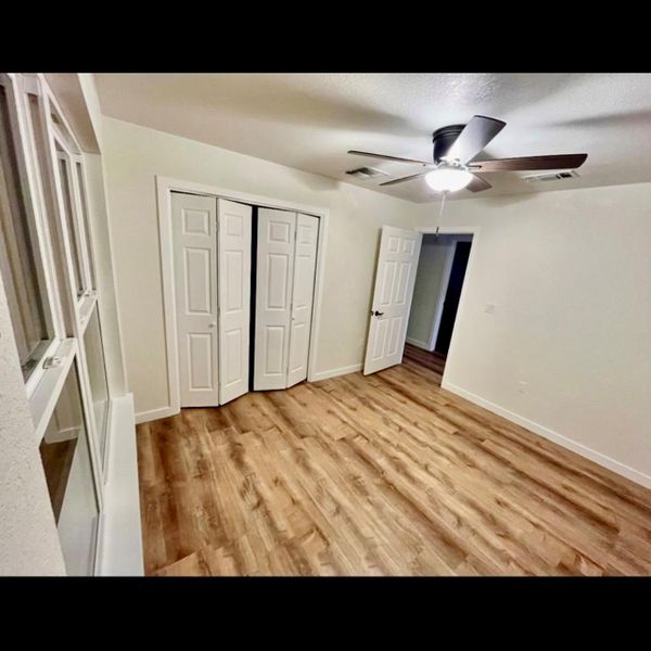 A pristine bedroom showcasing durable wood flooring and ample closet space.