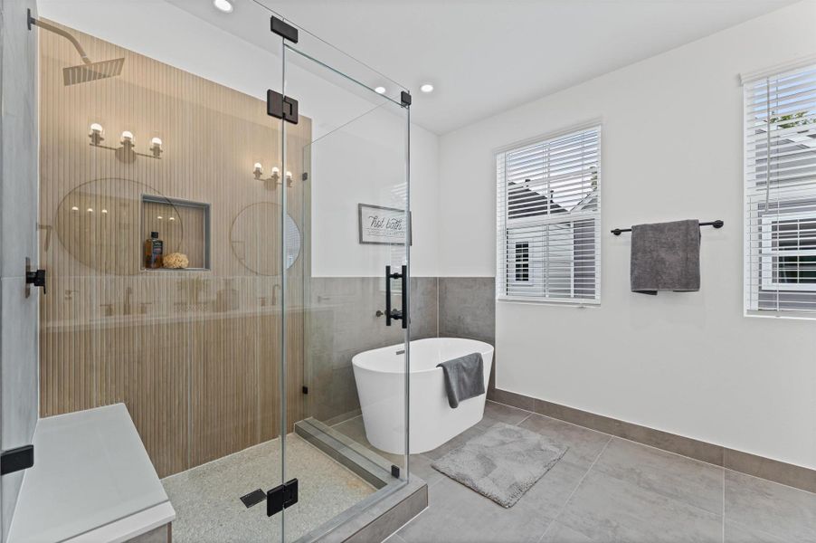 This luxurious primary bathroom blends modern elegance with spa-like comfort, featuring a spacious layout and contemporary selections throughout. A sleek double vanity with minimalist cabinetry and quartz countertops offers ample storage and style, while the glass-enclosed shower includes a built-in bench for added relaxation and convenience. The centerpiece is a sculptural freestanding soaking tub, perfectly positioned to invite unwinding after a long day.