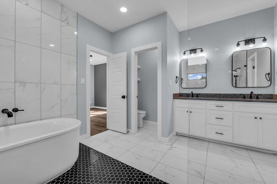 Full bath with a freestanding bath, tile walls, double vanity, recessed lighting, and light marble finish floors Full bath with a freestanding bath, tile walls, double vanity, recessed lighting, and light marble finish floors
