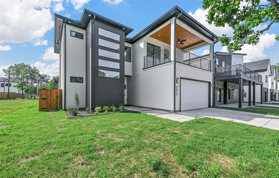 Contemporary house featuring a balcony, a garage, and a front lawn