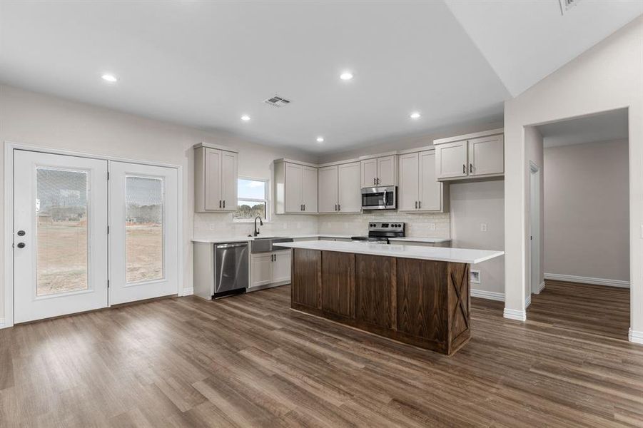 Kitchen with a kitchen island, appliances with stainless steel finishes, sink, and dark hardwood / wood-style floors Kitchen with a kitchen island, appliances with stainless steel finishes, sink, and dark hardwood / wood-style floors
