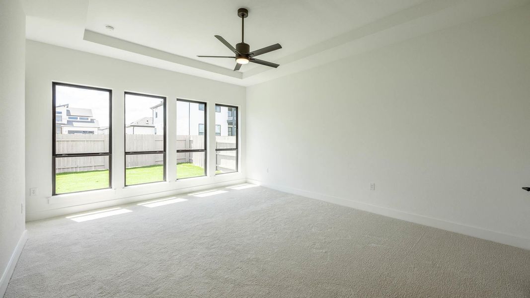Carpeted spare room with a tray ceiling and ceiling fan Carpeted spare room with a tray ceiling and ceiling fan