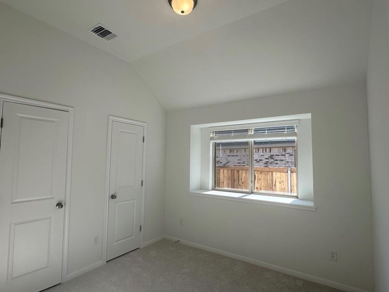 Unfurnished bedroom featuring vaulted ceiling and carpet flooring Unfurnished bedroom featuring vaulted ceiling and carpet flooring