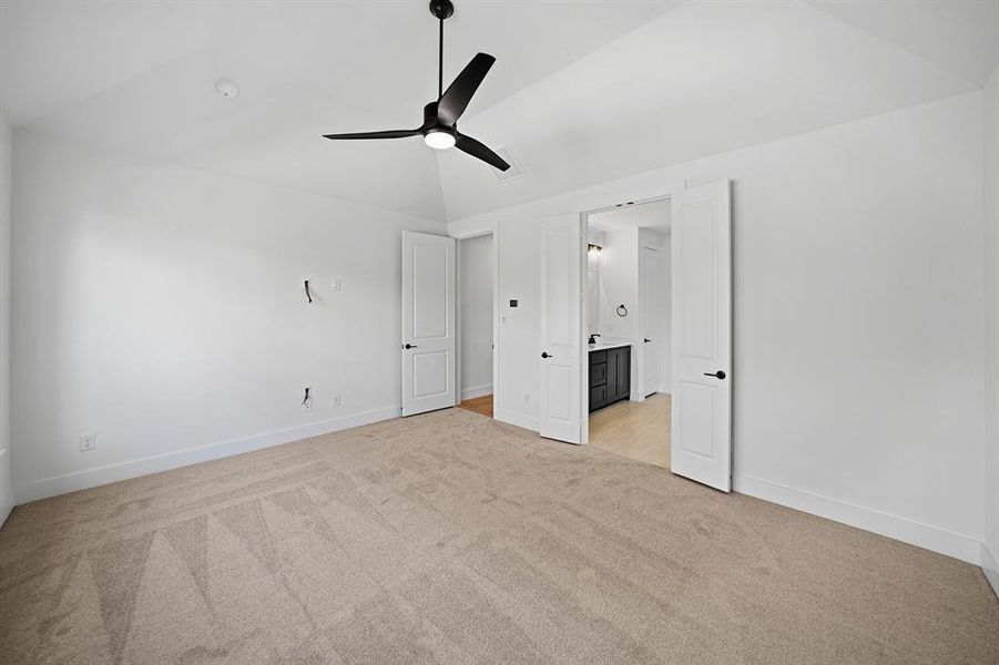 Unfurnished bedroom featuring light colored carpet, vaulted ceiling, ceiling fan, and connected bathroom Unfurnished bedroom featuring light colored carpet, vaulted ceiling, ceiling fan, and connected bathroom