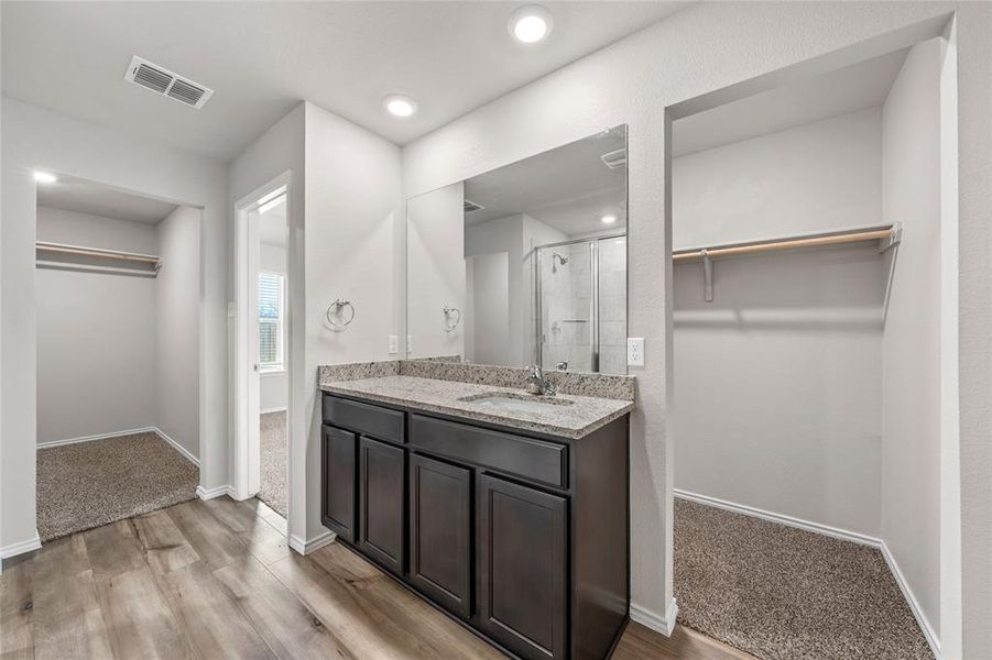 Full bath featuring a walk in closet, a shower stall, vanity, wood finished floors, and recessed lighting Full bath featuring a walk in closet, a shower stall, vanity, wood finished floors, and recessed lighting