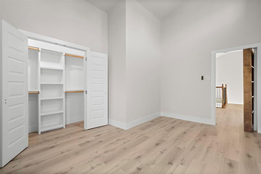 Unfurnished bedroom featuring a closet, a towering ceiling, and light wood-type flooring