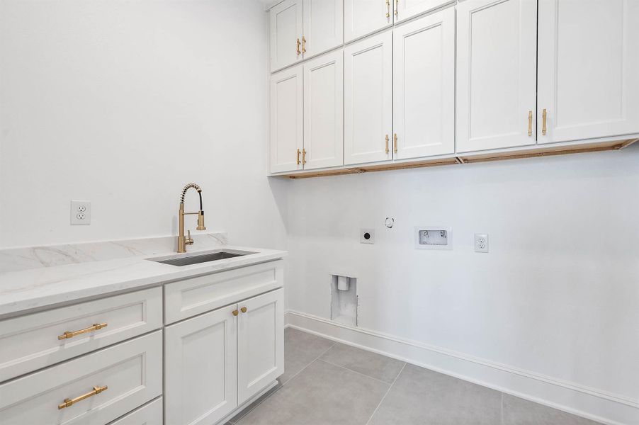 Utility room with plenty of cabinet space, a utility sink, washer and dryer connections, and gold cabinet hardware that adds a warm finishing touch.