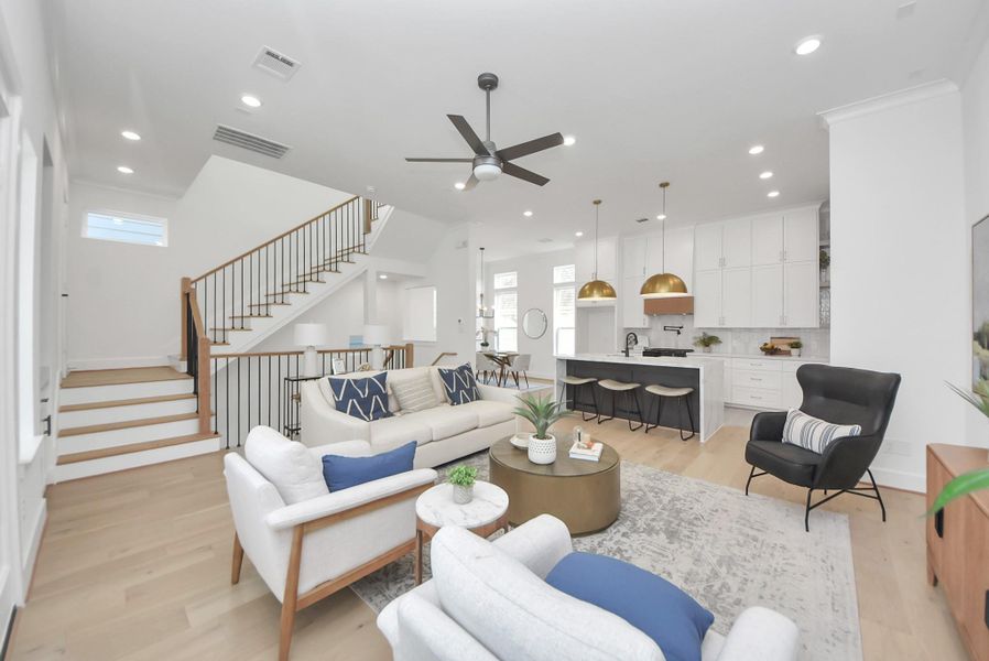 Step into this spacious, modern living area, where an open floor plan effortlessly combines a sleek kitchen and cozy seating. Natural light fills the room, highlighting the elegant staircase and neutral finishes. This inviting space is perfect for entertaining guests or enjoying quiet moments of relaxation.