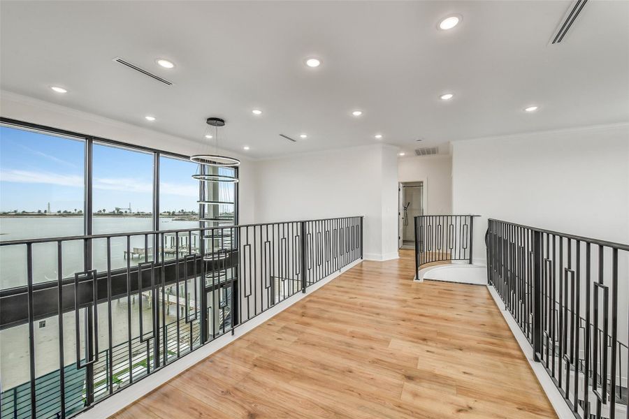 The upper landing delivers a view few homes can match. Overlooking the great room and bay, it keeps both levels visually connected while creating another striking architectural moment. The upper landing delivers a view few homes can match. Overlooking the great room and bay, it keeps both levels visually connected while creating another striking architectural moment.