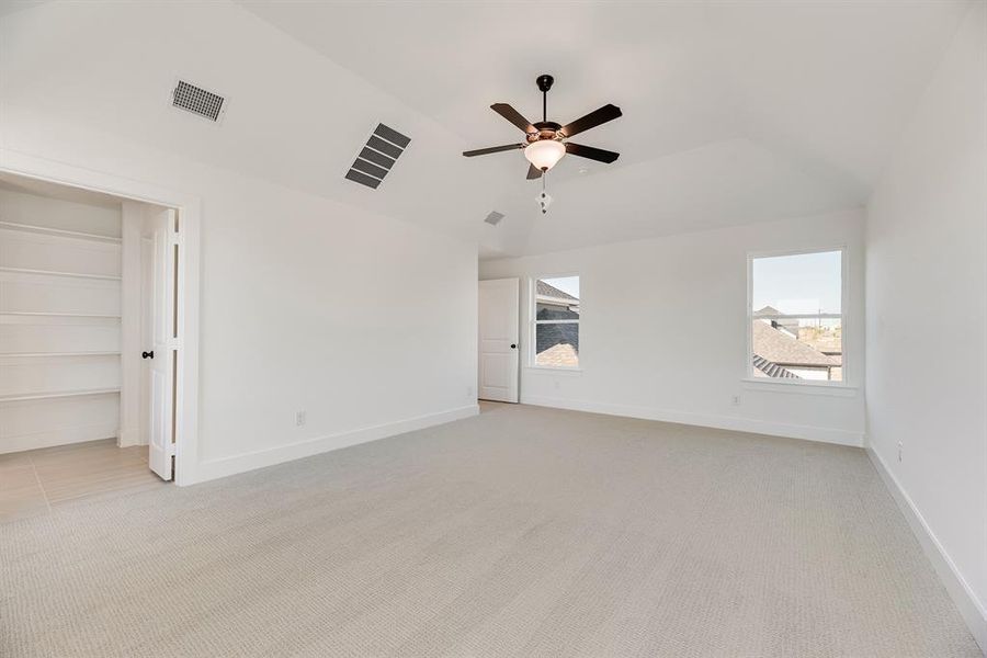Unfurnished bedroom with light colored carpet, ceiling fan, and lofted ceiling