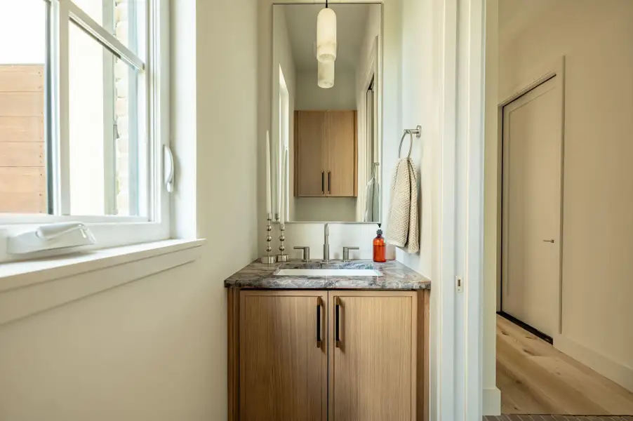 A customized vanity with stone counters anchors this sleek, modern powder room. A customized vanity with stone counters anchors this sleek, modern powder room.