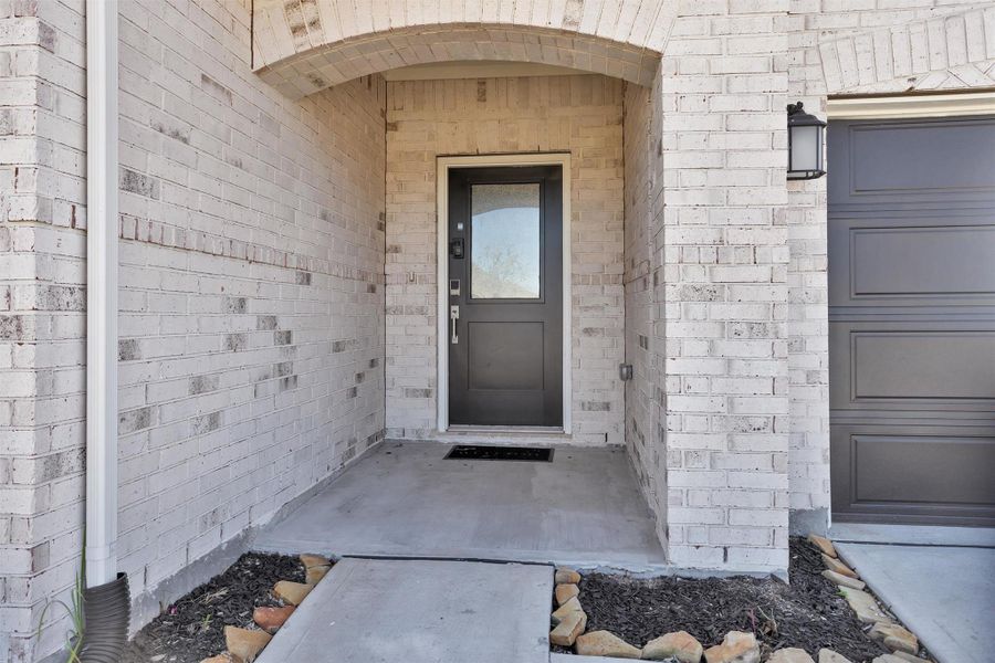 This inviting covered entry features a stylish modern front door, and private recessed porch.