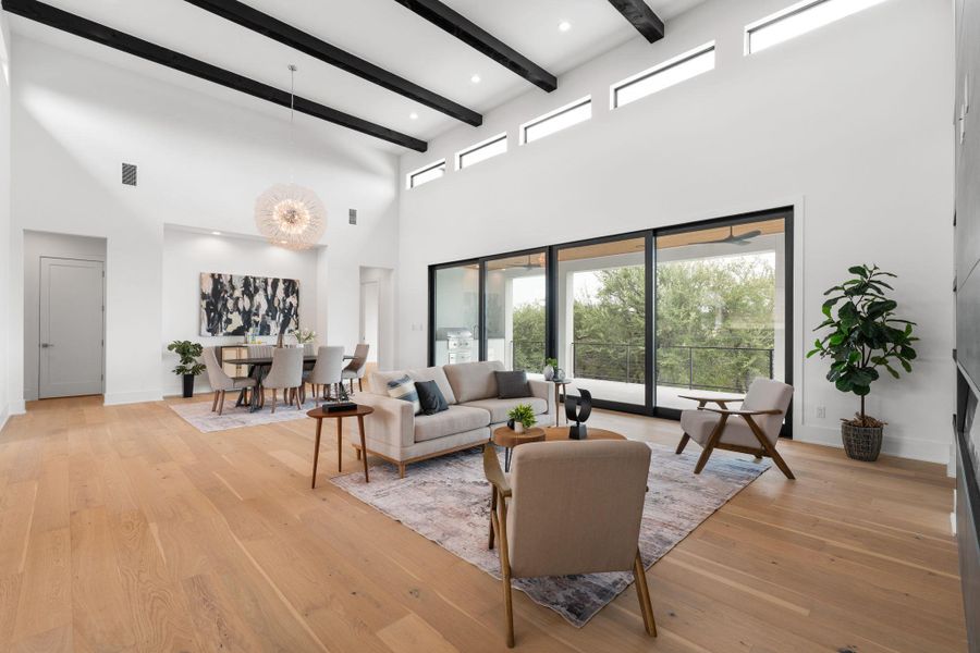 An open-concept living area with soaring ceilings and rich hardwood floors provides abundant natural light through a wall of sliding glass doors.