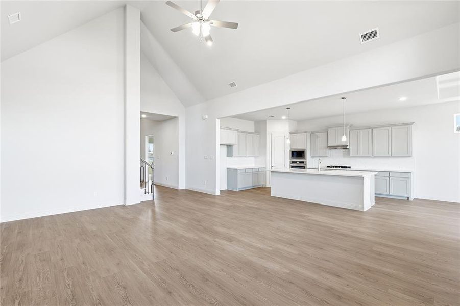 Unfurnished living room with high vaulted ceiling, light wood-style flooring, and ceiling fan Unfurnished living room with high vaulted ceiling, light wood-style flooring, and ceiling fan