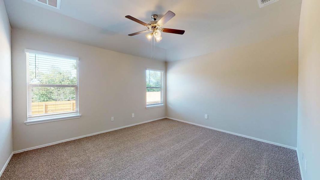 Spacious room featuring neutral carpeting, light-toned walls, and a ceiling fan with integrated lighting