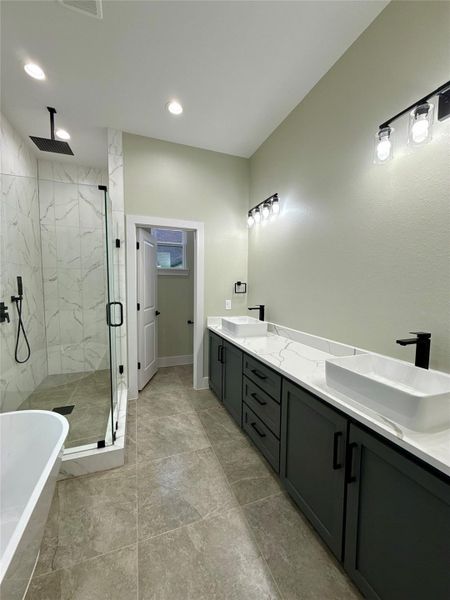 This modern bathroom features a spacious design with a large walk-in glass shower, elegant marble-look tiles, and sleek black fixtures. It includes a stylish double vanity with ample storage and contemporary lighting, creating a luxurious and functional space.