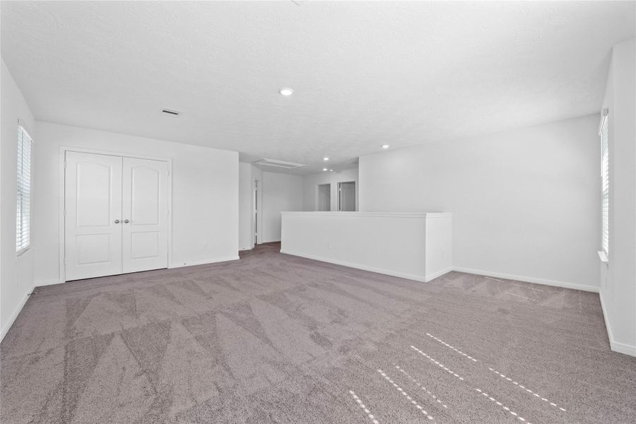 Another perspective of the Loft, showcasing the staircase, linen closet, and hallway leading to the secondary bedrooms.