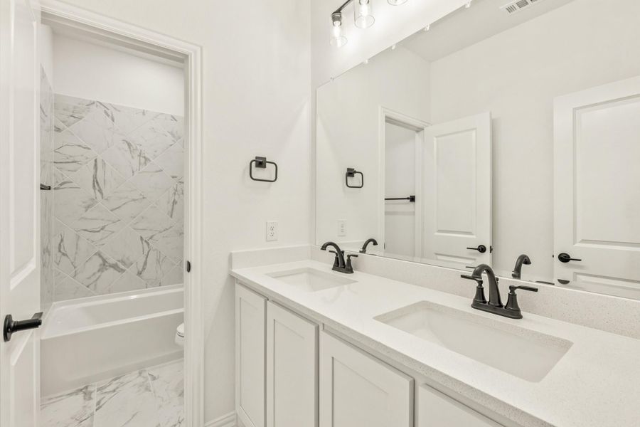 Bathroom with double sink vanity, white quartz countertop, and marble-tile shower with tub combo Bathroom with double sink vanity, white quartz countertop, and marble-tile shower with tub combo