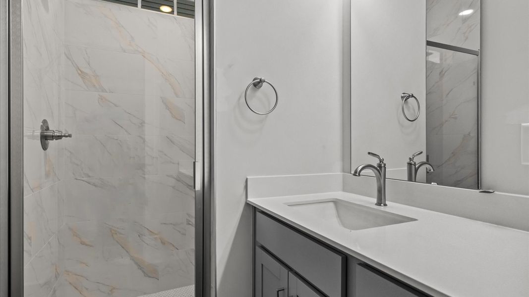 Memorable mornings begin in this elegant primary bathroom with tiled walk-in shower and double vanity