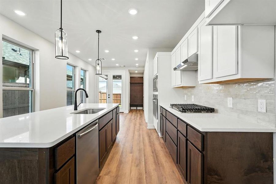 Kitchen featuring pendant lighting, light wood-style flooring, recessed lighting, stainless steel appliances, and dark brown cabinetry Kitchen featuring pendant lighting, light wood-style flooring, recessed lighting, stainless steel appliances, and dark brown cabinetry