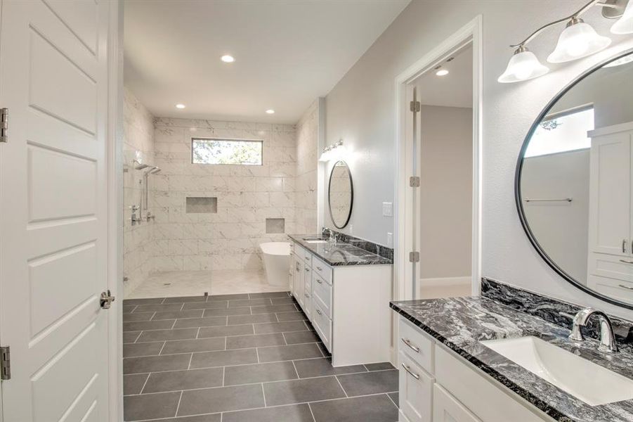 Bathroom featuring a tile shower, tile patterned floors, and vanity