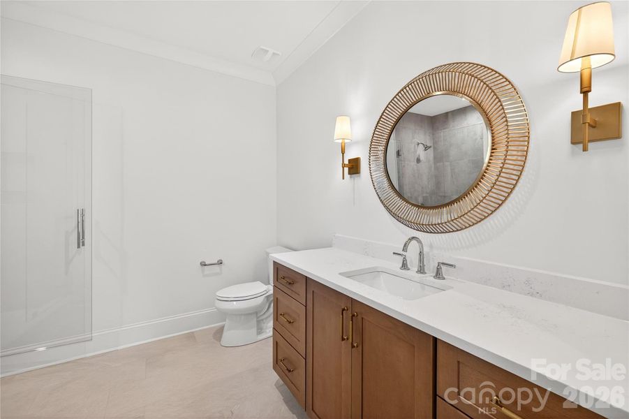 Bathroom #4 in-suite with gold round mirror, pretty white tile in the white shower.
