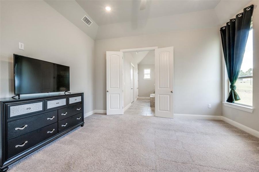 Carpeted bedroom with ceiling fan and vaulted ceiling