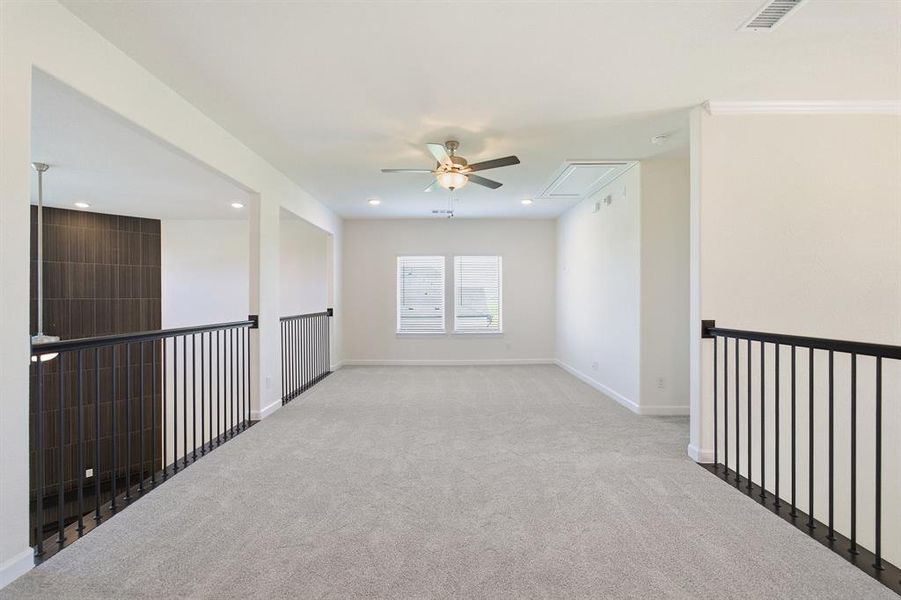 Spacious loft area featuring light gray carpet, multiple windows, recessed lighting, and a ceiling fan