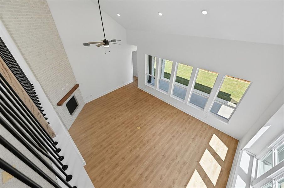 Unfurnished living room featuring high vaulted ceiling, recessed lighting, wood finished floors, a fireplace, and a ceiling fan Unfurnished living room featuring high vaulted ceiling, recessed lighting, wood finished floors, a fireplace, and a ceiling fan