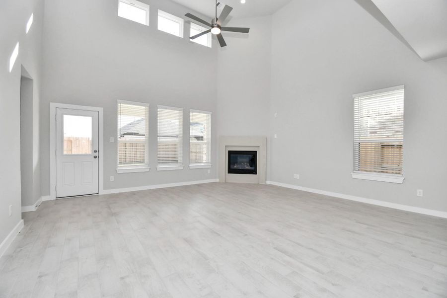 Relax and unwind in this inviting family room, illuminated by abundant natural light streaming in through tall windows, complemented by high ceilings and stunning flooring. Stay comfortable year-round with the gentle breeze from the ceiling fan, creating the perfect atmosphere for family gatherings. Sample photo of completed home with similar floor plan. Actual colors and selections may vary.