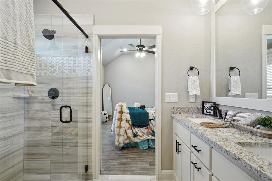 Bathroom featuring lofted ceiling, dual bowl vanity, wood-type flooring, an enclosed shower, and ceiling fan