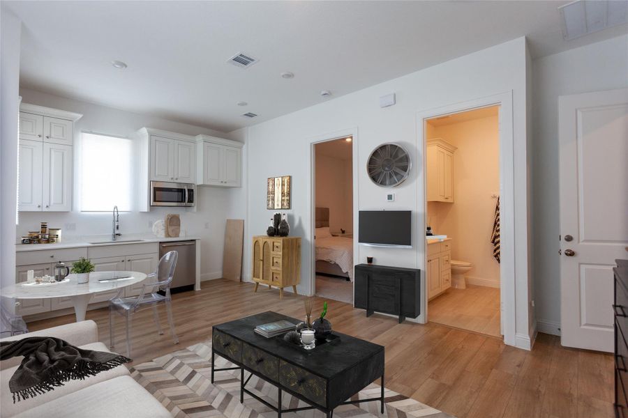 Separate quarters with its own entrance!!Cozy open-plan living space with a modern kitchen featuring white cabinetry and stainless steel appliances. There's a small dining area, a comfortable living room with access to a bedroom and bathroom.