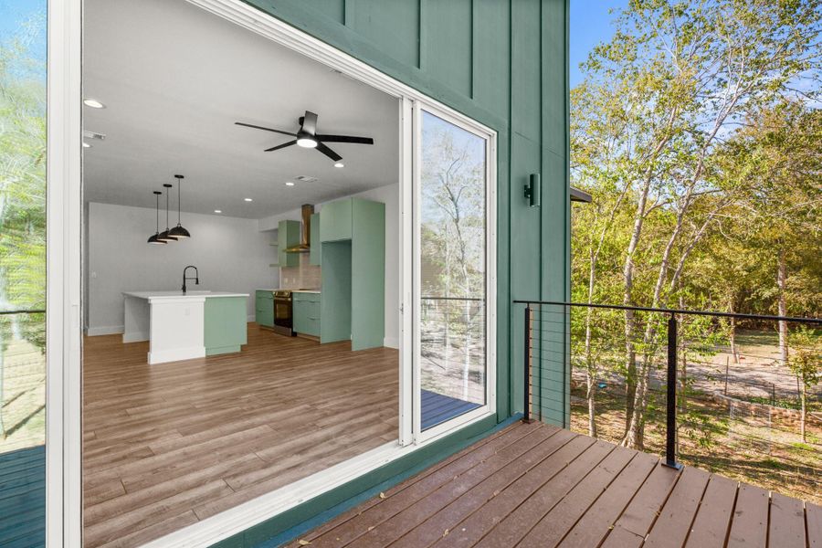 Wooden terrace with a ceiling fan and view of wooded area