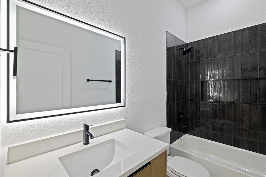 Bathroom with a textured wall, vanity, and bathtub / shower combination
