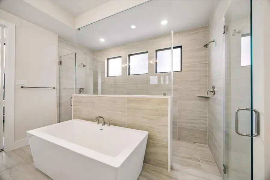 PRIMARY BATH FEATURES A FREESTANDING SOAKING TUB, OVERSIZED WALK-IN SHOWER, FLOOR-TO-CEILING TILE, AND MULTIPLE WINDOWS FOR NATURAL LIGHT. PRIMARY BATH FEATURES A FREESTANDING SOAKING TUB, OVERSIZED WALK-IN SHOWER, FLOOR-TO-CEILING TILE, AND MULTIPLE WINDOWS FOR NATURAL LIGHT.