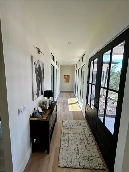 Hallway with light wood-style floors and french doors Hallway with light wood-style floors and french doors