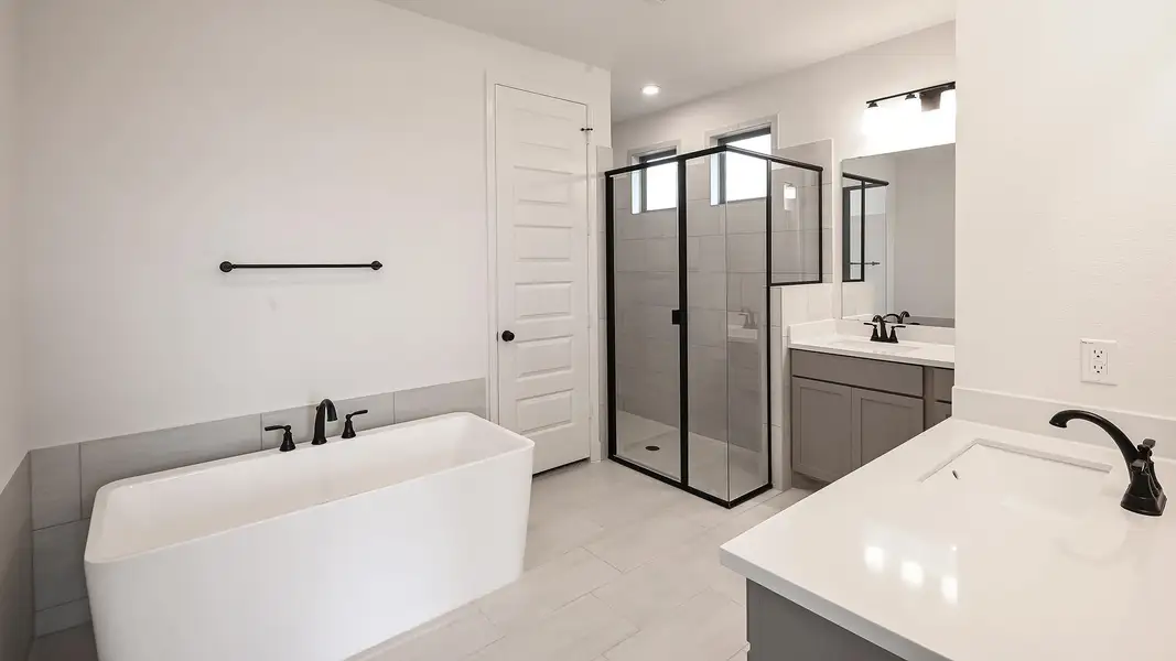 Full bathroom with two vanities, a stall shower, and a freestanding tub