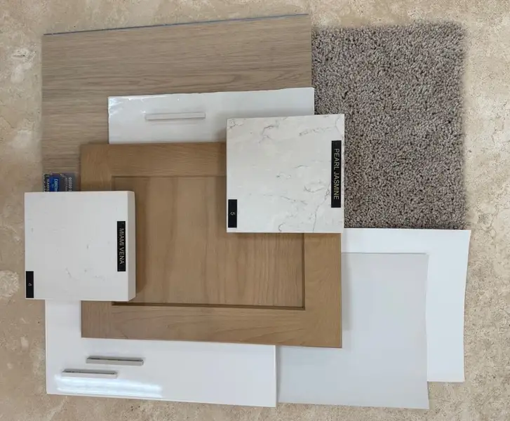 Home design material samples including wood cabinet doors, white quartz countertop swatches, and taupe carpet sample arranged flat lay Home design material samples including wood cabinet doors, white quartz countertop swatches, and taupe carpet sample arranged flat lay