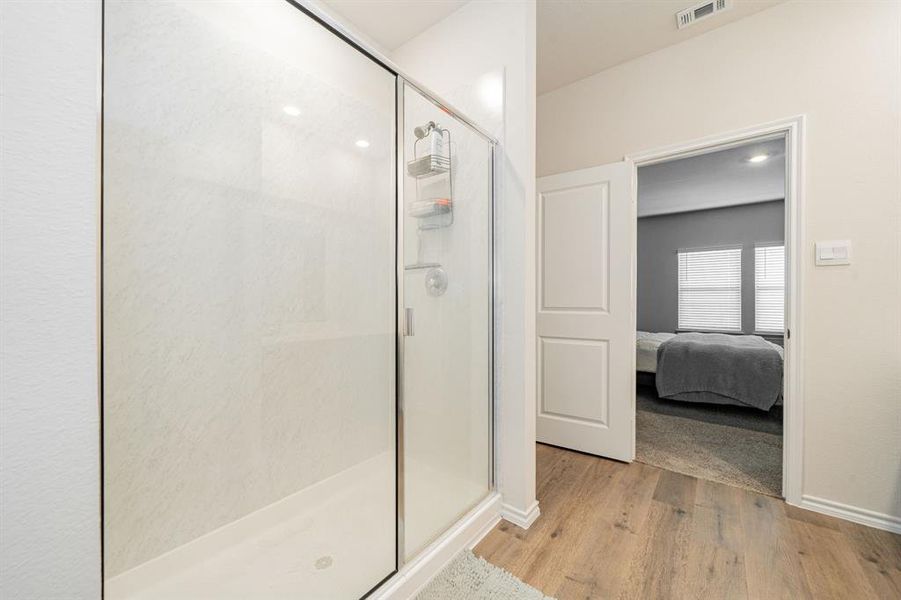 Full bathroom featuring a shower stall, light LVP flooring, and ensuite bath Full bathroom featuring a shower stall, light LVP flooring, and ensuite bath