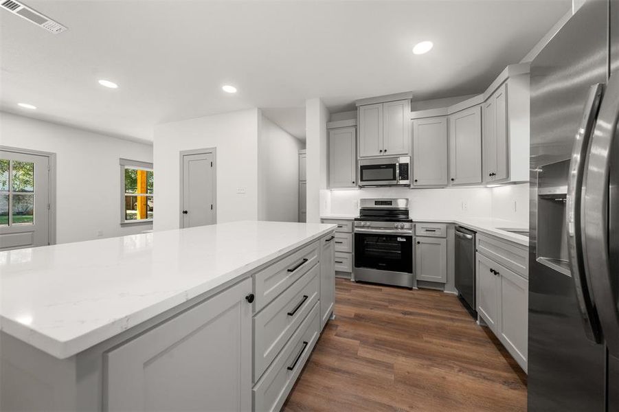 Kitchen featuring appliances with stainless steel finishes, recessed lighting, dark wood-style flooring, gray cabinets, and light stone counters