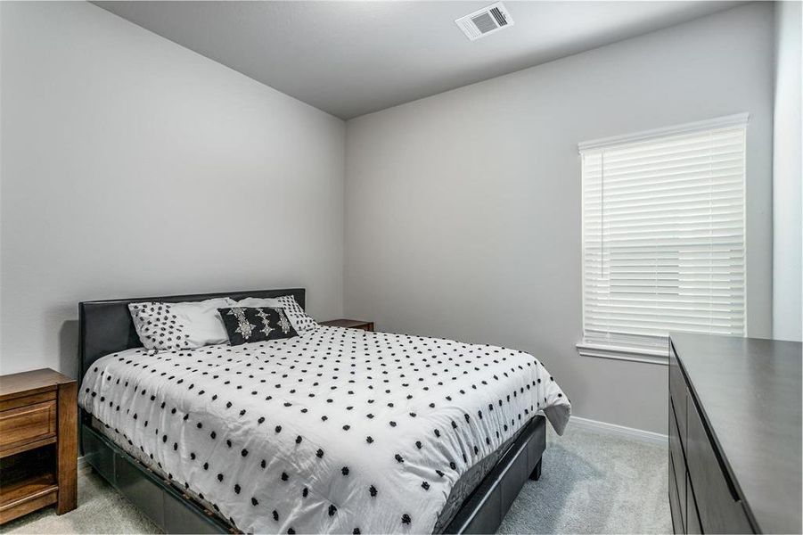 This additional bedroom offers a tranquil retreat with soft carpeting and a large window that fills the room with natural light. Ideal for a guest room, home office, or children's room, the space is designed for comfort and functionality, ensuring a peaceful environment for rest or study. **This image is from another Saratoga Home - Mockingbird floorplan.**