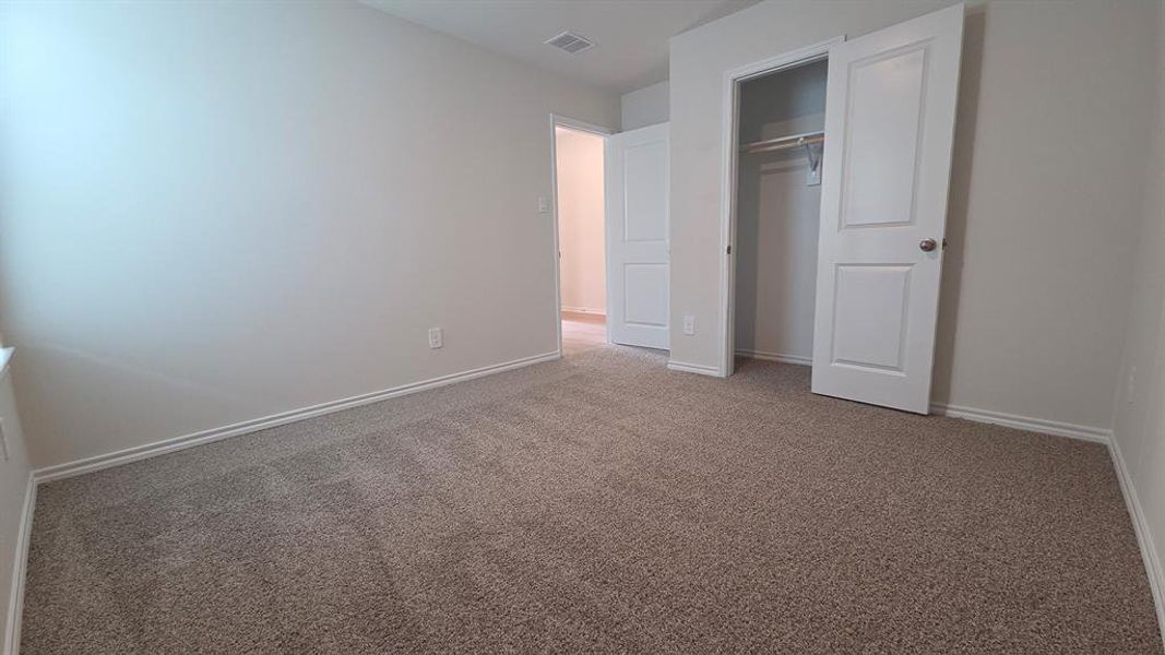 Carpeted room featuring light-colored walls, white trim, and a bi-fold closet with an interior hanging rod