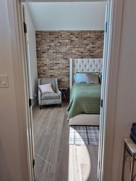 Bedroom with wood finished floors and a textured wall