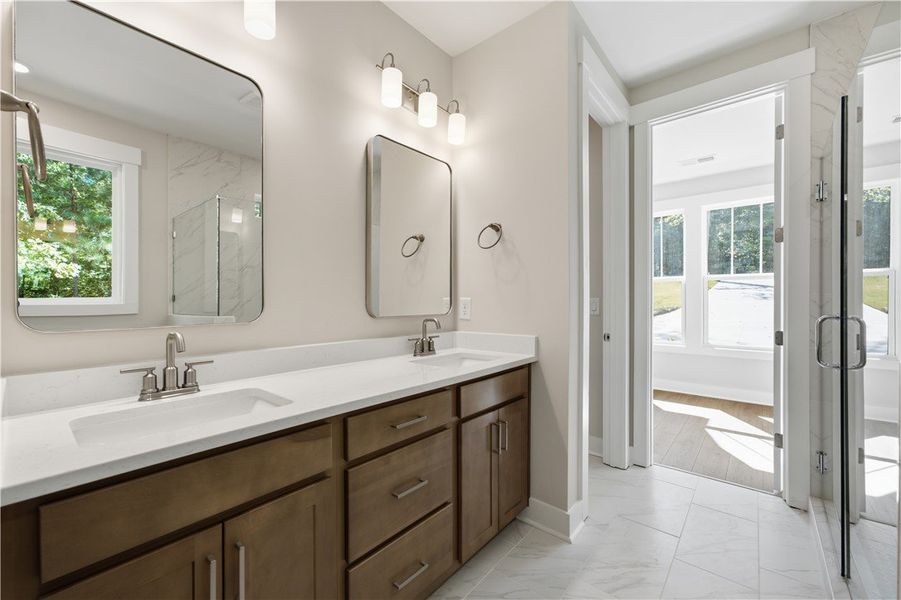 A spacious double vanity features sleek stone coun
