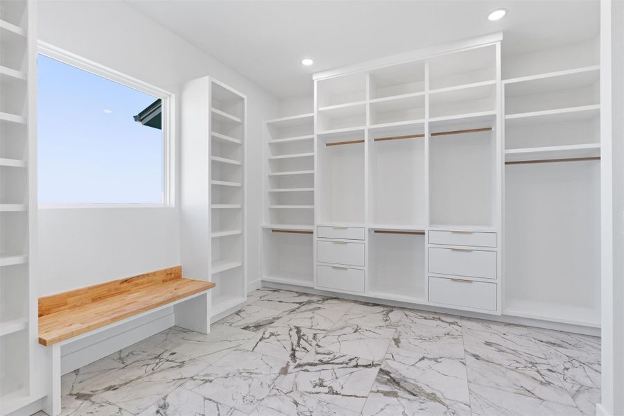 Spacious closet featuring light marble finish flooring