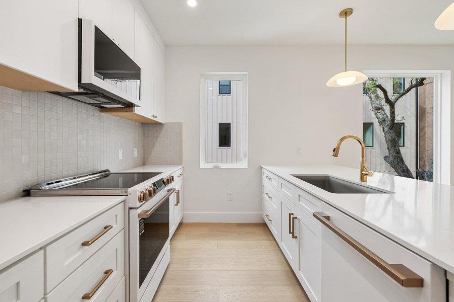 Kitchen featuring white appliances, white cabinetry, light stone counters, and light wood-style flooring