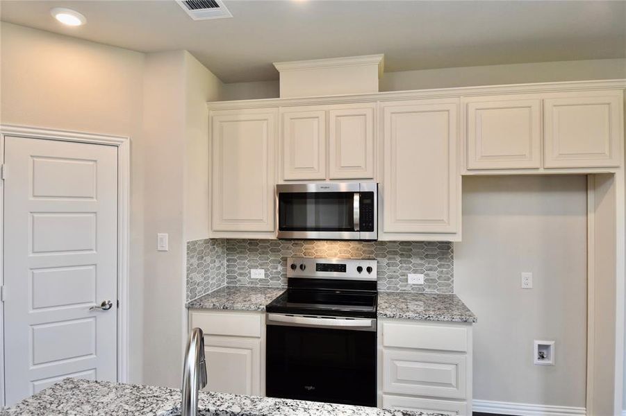Kitchen with stainless steel appliances, light stone counters, tasteful backsplash, white cabinetry, and recessed lighting